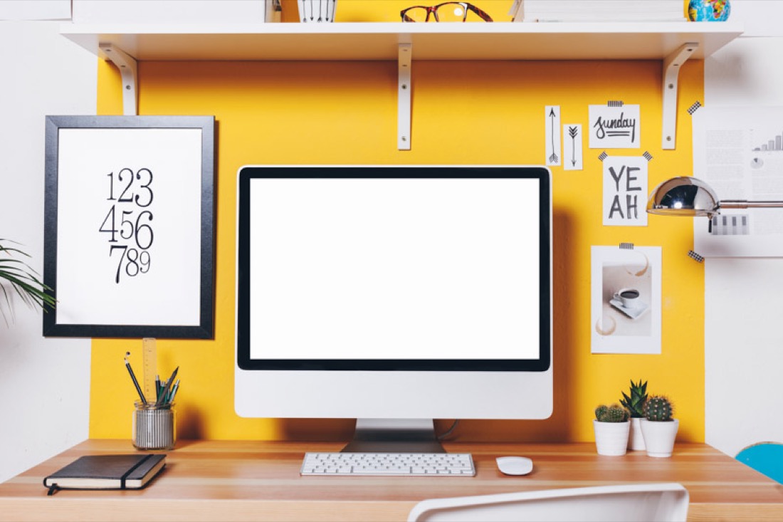 Workspace in yellow background with computer with notes.