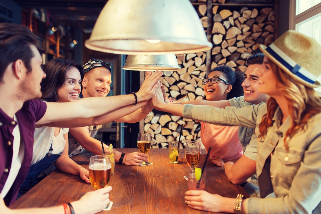 Group sitting together and doing high-five at a pub