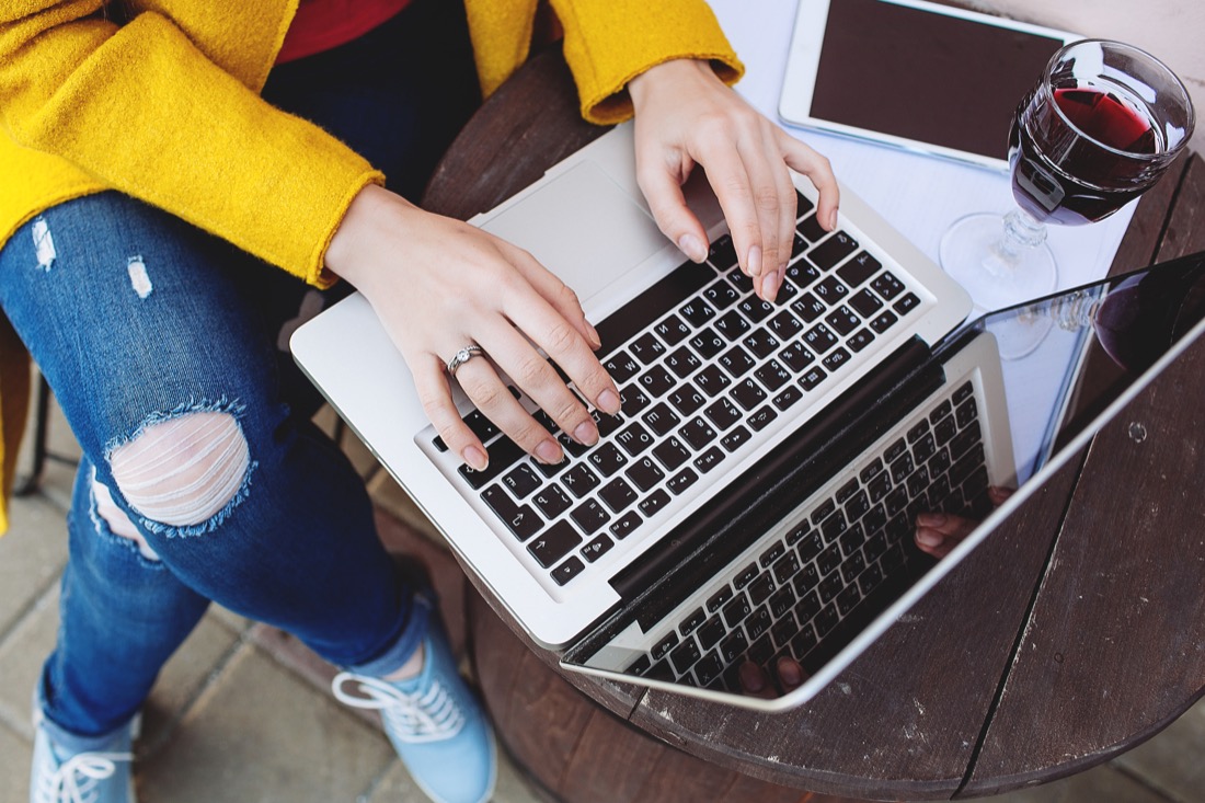 Woman wearing yellow typing on laptop