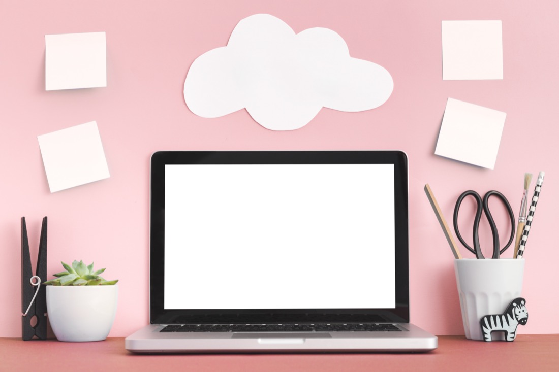 Pink background with laptop and paper clouds. work.