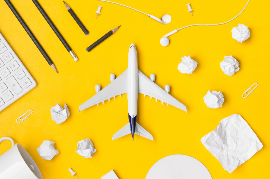 Airplane toy with pencil paper note, paper clip, earphone, calculator on a yellow background