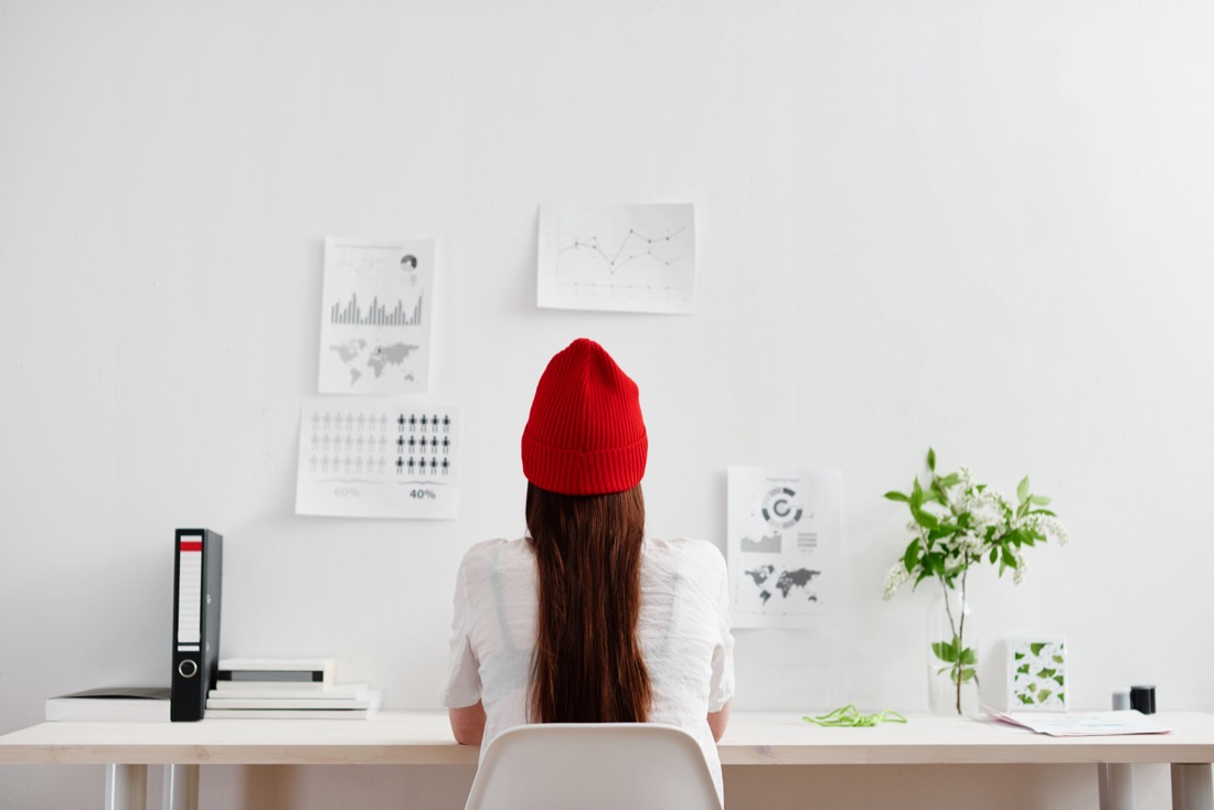 Lady in red hat working in a white office space.