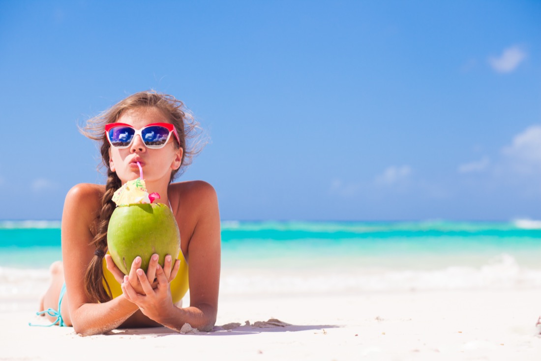 Woman with a coconut at the beach.