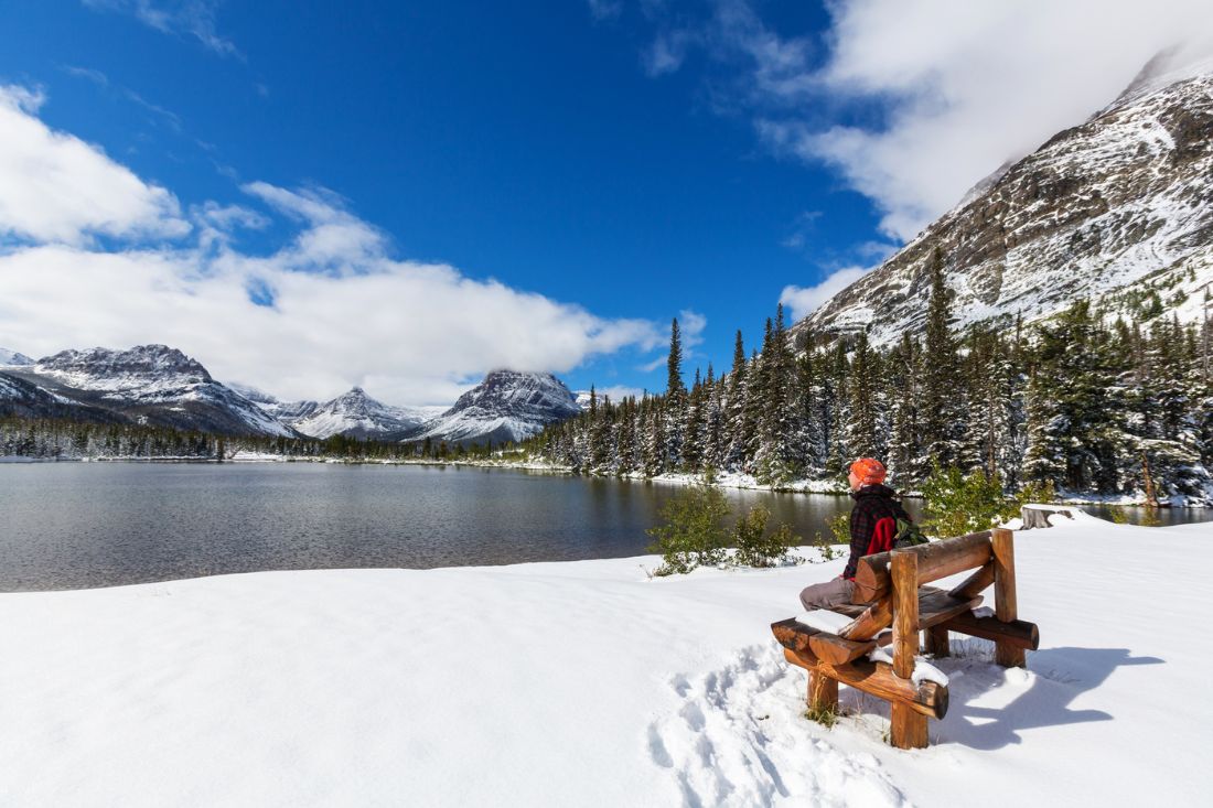 Person sitting in bench during winter in Glacier National Park.