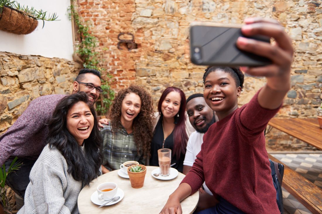 Diverse group of friends taking a selfie at a cafe.
