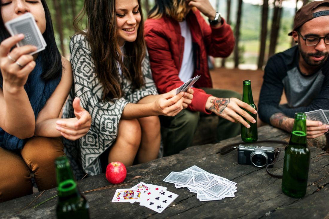 Group of friends playing card games during camping.