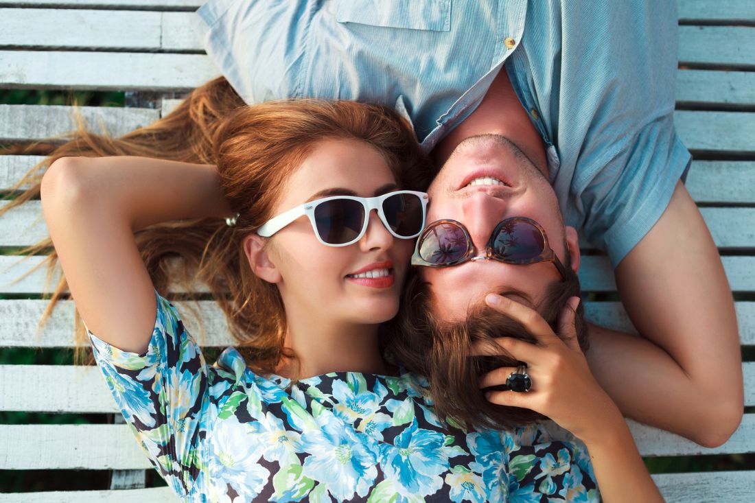 Young couple wearing sunglasses and lying down.