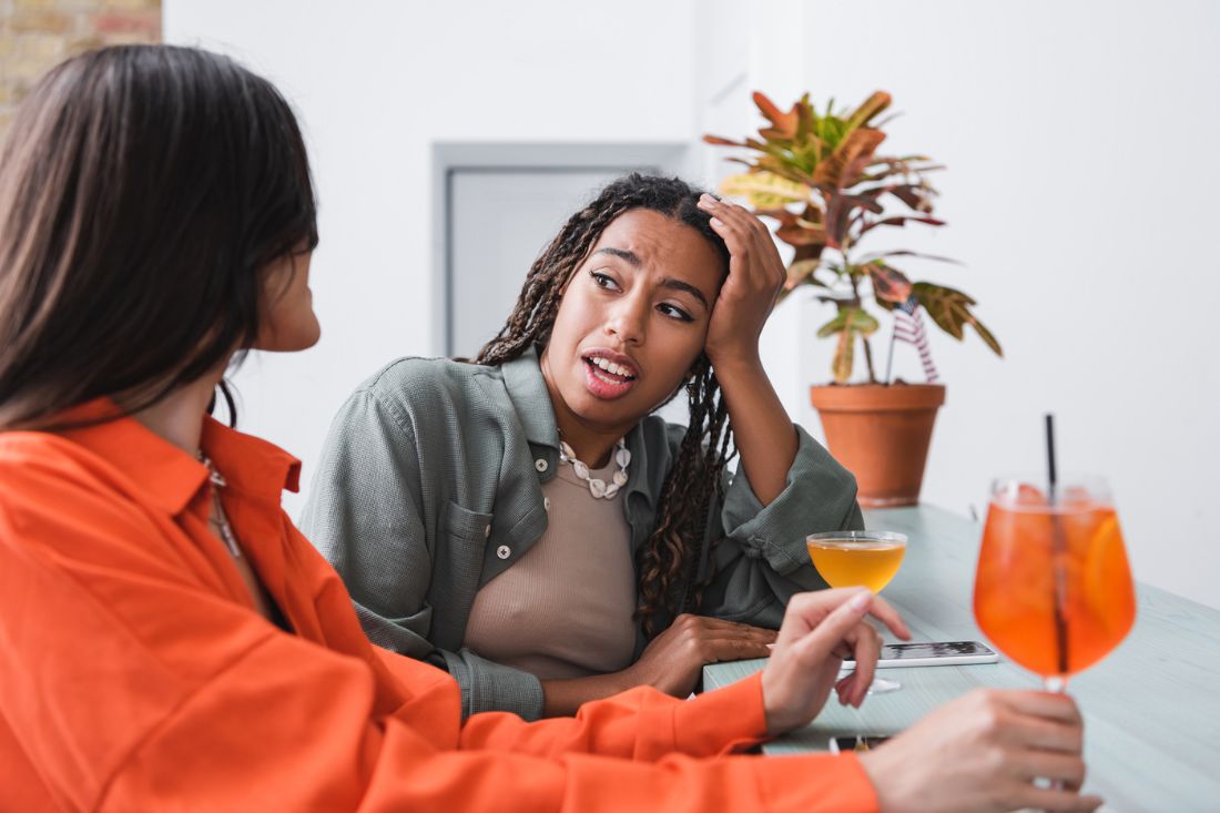 African American woman talking to girlfriend while having cocktail.