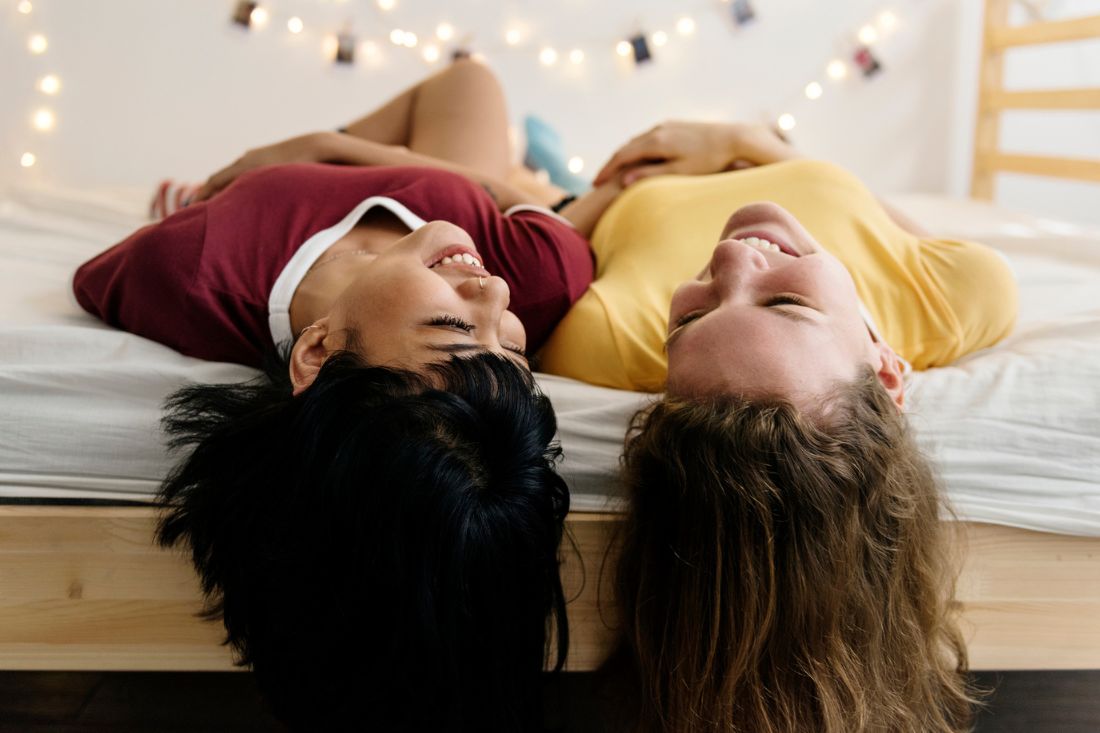 Two woman lying on the bed and laughing.