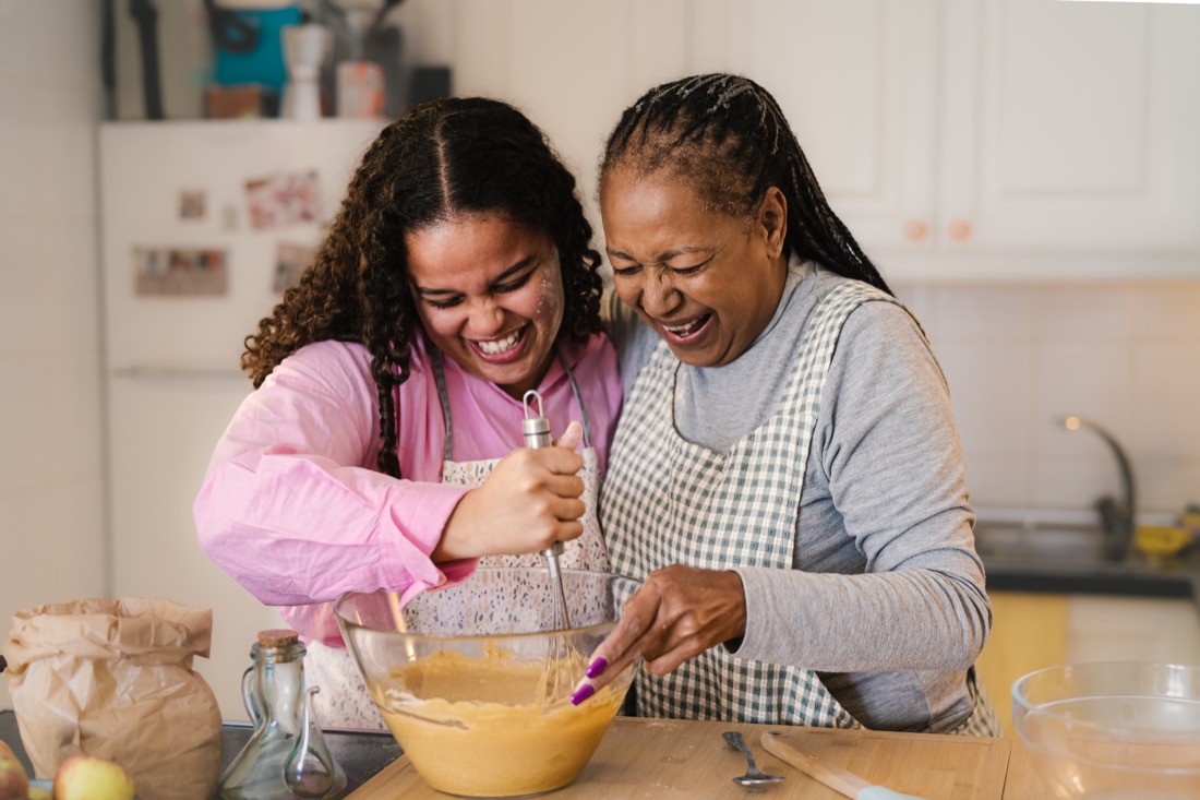 Happy Black mother and daughter having fun preparing a homemade dessert