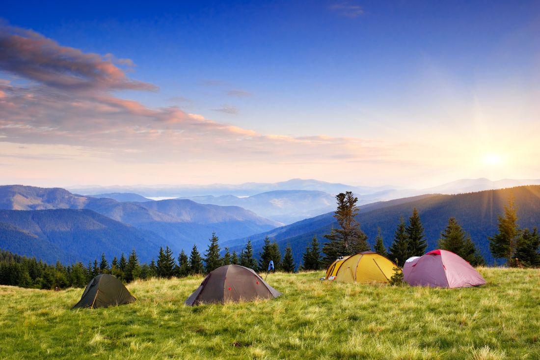 4 camping tents of difference colors on a mountain.
