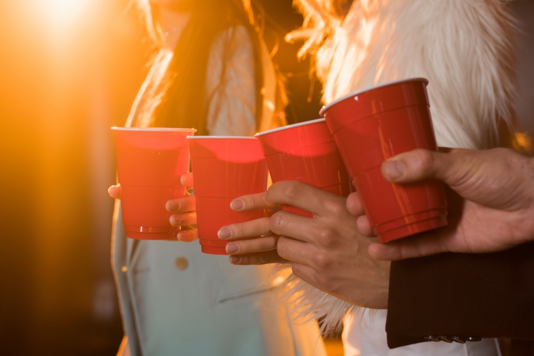 Cropped view of friends toasting plastic red cups 