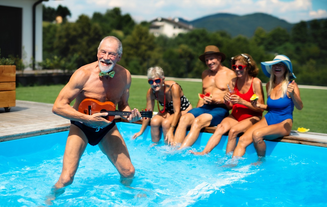 Group of cheerful seniors by swimming pool outdoors in backyard, party concept
