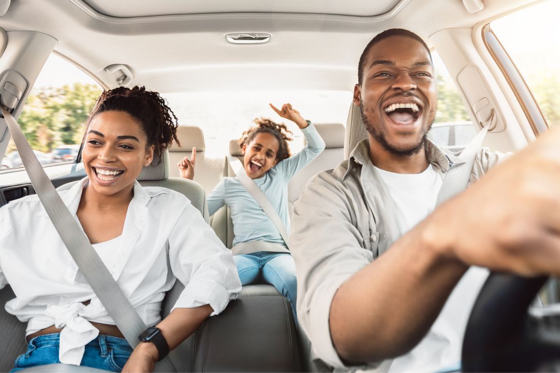 Happy black family with three members having fun and singing during car ride.