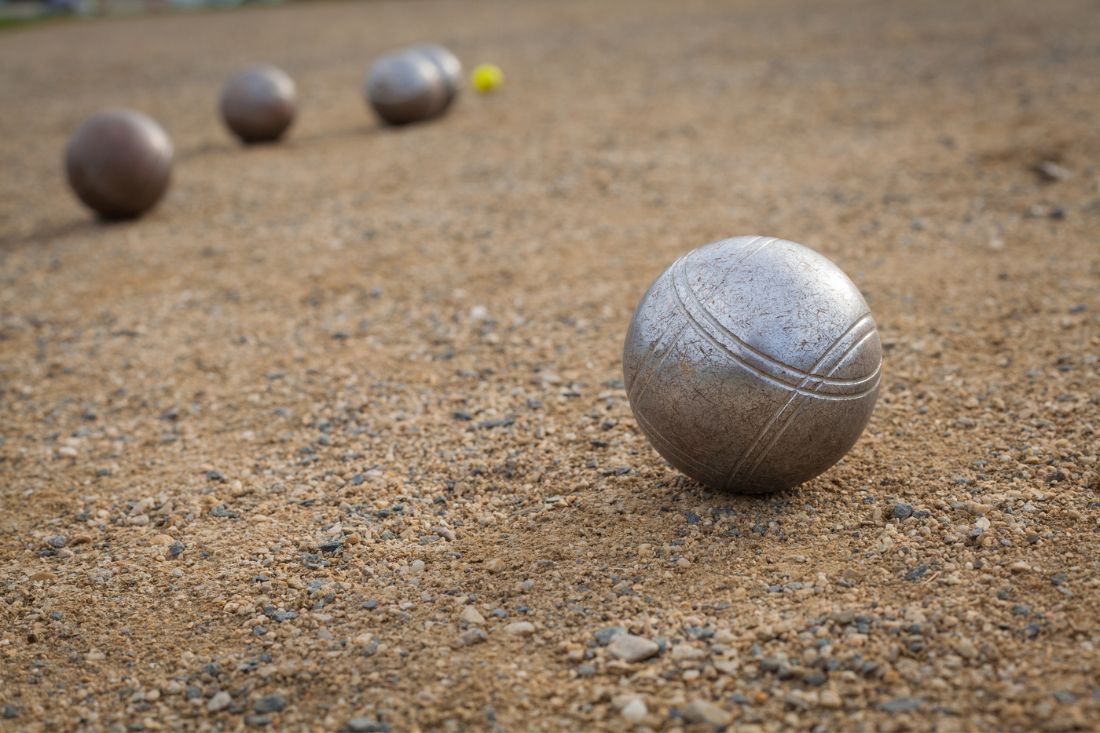 Silver colored bocce balls on sand.