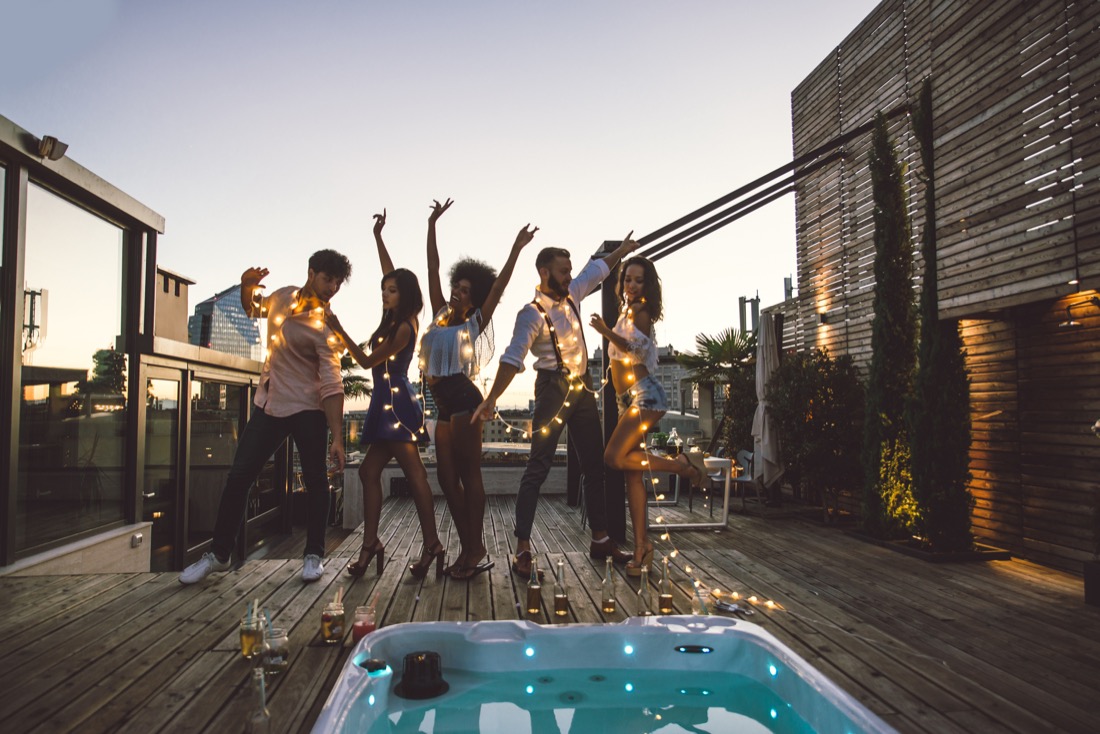 Friends dancing by hot tub draped in fairy lights